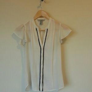 Cream sheer blouse with black trim.